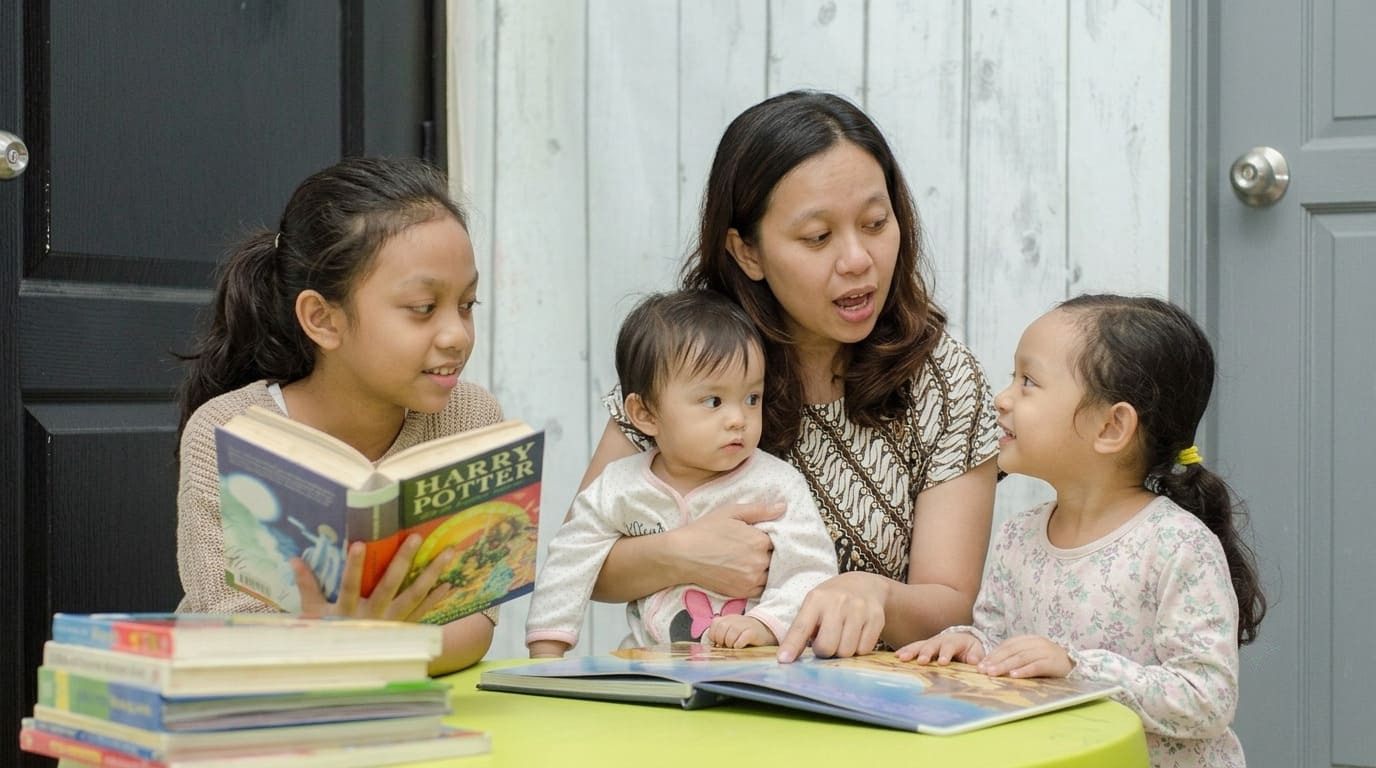 Ibu mengajak anak usia sekitar 2 tahun berbicara sambil membaca buku bergambar untuk menstimulasi perkembangan bahasa dan kemampuan bicara.